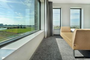 a room with a couch and a large window at Van der Valk Hotel Nijmegen-Lent in Nijmegen