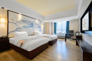a hotel room with two beds and a large painting on the wall at Foshan Rezen Select Pasonda Hotel in Foshan
