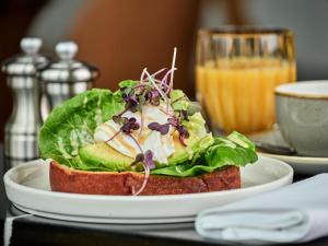 a sandwich on a plate on a table with a drink at Crowne Plaza - Warsaw - The HUB, an IHG Hotel in Warsaw