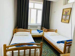 two twin beds in a room with a window at Hotel-RIVERSIDE in Tashkent
