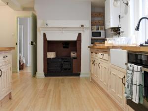 a kitchen with wooden floors and a kitchen with a stove at Brook Cottage in Dawlish