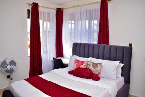 a bedroom with a large bed with red curtains at Rozy Penthouse in Kisumu