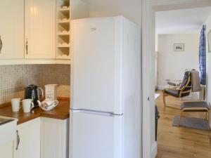 a white refrigerator in a kitchen with a table at Dollys Cottage in Ovingham