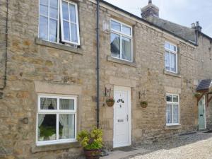 an old stone house with white doors and windows at Dollys Cottage in Ovingham