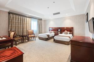 a hotel room with two beds and a desk at Chairmen Hotel in Doha