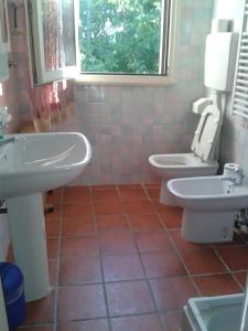 bagno con 2 lavandini, servizi igienici e finestra di B&B Le Due Rocche a Maiolo