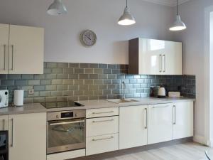 a kitchen with white cabinets and a clock on the wall at Charlotte Street in Ayr