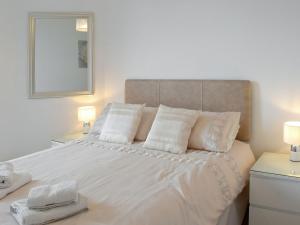 ein weißes Bett mit weißen Kissen und einem Spiegel in der Unterkunft Charlotte Street in Ayr