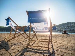 a chair and a sign sitting on the beach at Waterfront House in Dartmouth