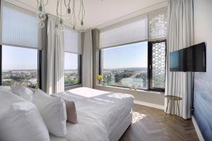 a bedroom with a bed and a tv and windows at Van der Valk Hotel Nijmegen-Lent in Nijmegen