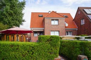 a house with a hedge and an umbrella at Hotel Pension Loose in Borkum