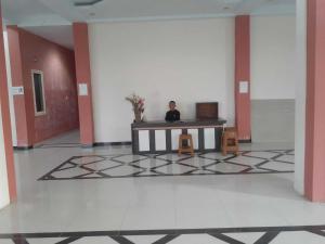 un homme assis à une table dans une pièce dans l'établissement EXPRESS O 91662 Kost Rumah Kaca, à Mirue