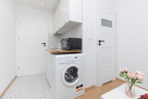 a white laundry room with a washer and dryer at Micro Apartment near Fort Mokotów in Warsaw