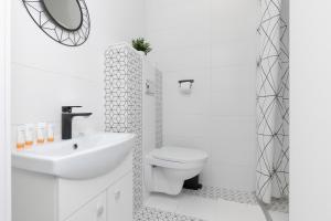 a white bathroom with a toilet and a sink at Micro Apartment near Fort Mokotów in Warsaw