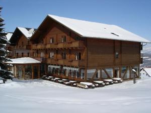ein großes Holzgebäude mit Schnee auf dem Dach in der Unterkunft Enzianhof in Ligist