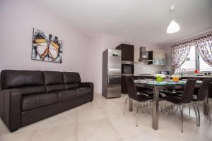 a living room with a couch and a table with chairs at The Waves Apartment Marsaxlokk in Marsaxlokk