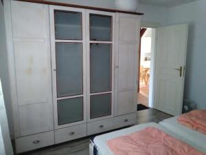 a white cabinet with glass doors in a bedroom at Seeperle 1, Ferienhaus am Leuchtturm mit traumhaftem Garten in Ording