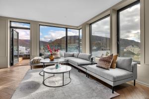 a living room with couches and tables and large windows at Penthouse in Downtown Tromsø NEW in Tromsø