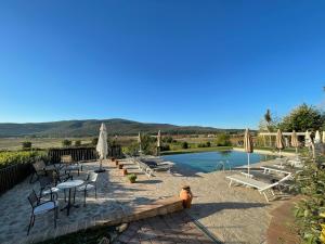 a pool with chairs and tables and umbrellas next to at IL COLOMBAIO WINERY & Rooms in Monteriggioni