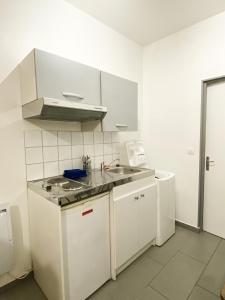 Biała kuchnia ze zlewem i kuchenką w obiekcie Bienvenue dans le centre ville d’Amiens w Amiens +2 zdjęcia