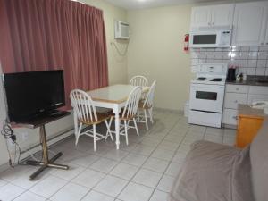 a kitchen with a table and chairs and a refrigerator at Canadas Best Value Inn & Suites-Vernon in Vernon
