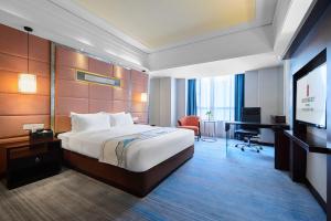 a hotel room with a bed and a desk and a television at Foshan Rezen Select Pasonda Hotel in Foshan