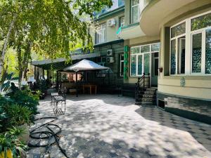 a patio of a house with chairs and an umbrella at Hotel-RIVERSIDE in Tashkent