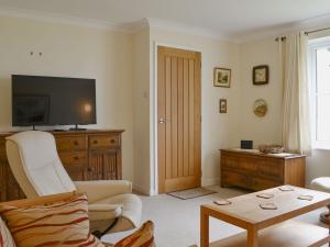 ein Wohnzimmer mit einem TV, einem Stuhl und einem Tisch in der Unterkunft Meadowcroft Cottage in Bowness-on-Windermere