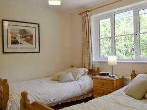 a bedroom with two beds and a window at Meadowcroft Cottage in Bowness-on-Windermere