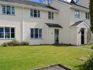 a large white house with a grass yard at Meadowcroft Cottage in Bowness-on-Windermere