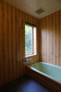 een badkamer met een bad en een raam bij RENEST in Kobe