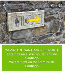 een teken op een stenen muur met een gele pijl bij Agroturismo Erlete Goikoa -ESTAMOS EN EL CAMINO DE SANTIAGO -WE ARE ON THE CAMINO DE SANTIAGO in Deba