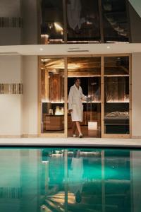 a man in a lab coat standing next to a swimming pool at Hotel Wiesnerhof in Vipiteno