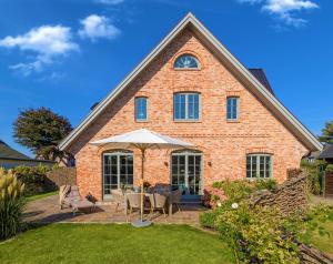 a brick house with a table and chairs and an umbrella at Ferienhaus SylterLiebe in Tinnum