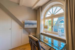 a home office with a glass desk and a window at Ferienhaus SylterLiebe in Tinnum