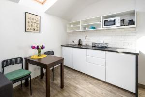 una cucina con mobili bianchi, un tavolo e un bancone di Modern aparment in the very central location 19 a Cracovia Altre 3 foto