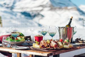 a table with a plate of food and wine glasses at Riffelhaus 1853 in Zermatt