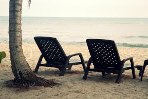 
two beach chairs sitting on the beach next to the ocean at Tayrona Tented Lodge in Guachaca
