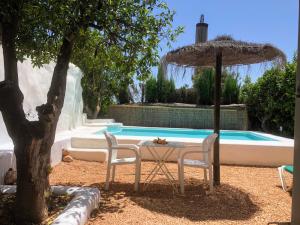 una mesa y dos sillas junto a una piscina en Casa Cueva El Naranjo Rocabella, en El Chorro