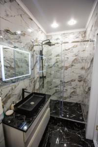 een badkamer met een wastafel en een douche met een glazen deur bij El-Tau in Ekibastuz