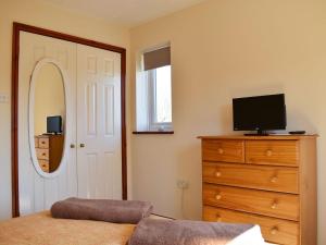 a bedroom with a bed and a dresser with a television at The Little House in Briston