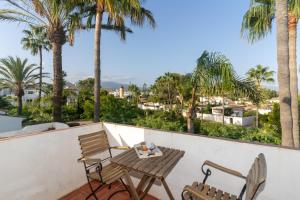 balkon ze stołem, krzesłami i palmami w obiekcie Townhouse beachfront in Costalita w mieście Estepona
