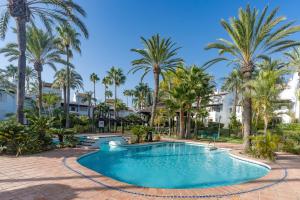 basen z palmami i budynkami w obiekcie Townhouse beachfront in Costalita w mieście Estepona