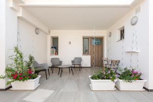 Maresidence Rooms & Breakfast في توري بالي: غرفة بها ثلاثة خزاف من النباتات وطاولة وكراسي
