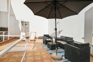 ein Wohnzimmer mit einem Sofa und einem Sonnenschirm in der Unterkunft Malasaña 51, new art apartment, breakfast included, historic center, quite neighborhood, ML in Málaga