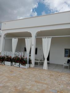 ein weißes Gebäude mit weißen Vorhängen und roten Blumen in der Unterkunft U Ceccenate in Montalbano