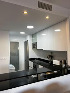 a kitchen with white cabinets and a black counter top at Flamenca Village by Mar Holidays in Orihuela
