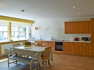 a kitchen with wooden cabinets and a table and chairs at Alice Cottage in Embleton