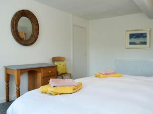 a bedroom with a bed with a table and a mirror at Alice Cottage in Embleton