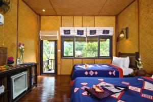 una camera con due letti in una stanza con finestra di Hmong Hilltribe Lodge a Mae Rim